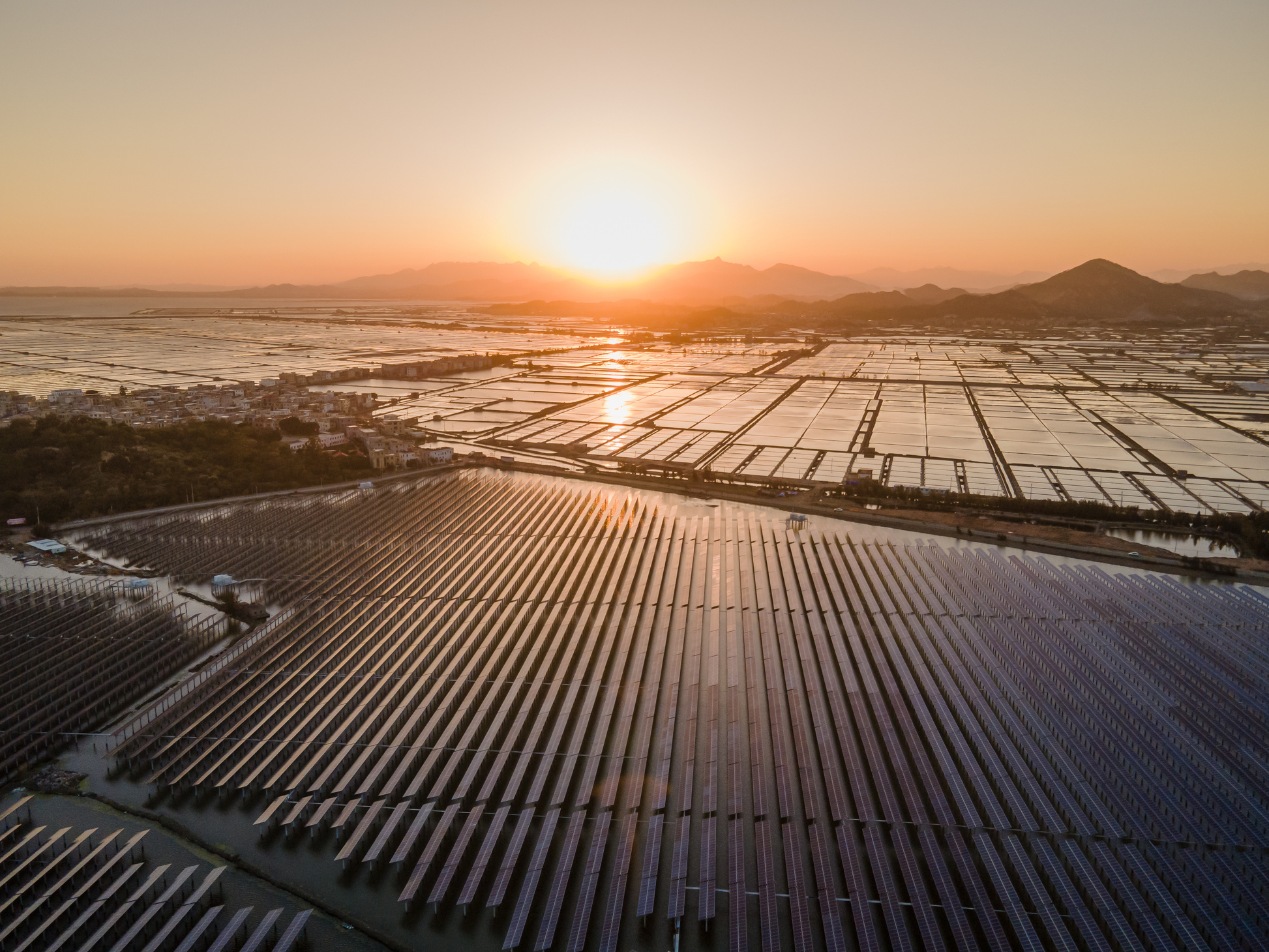Aerial photography of the whole seaside photovoltaic solar power plant at dusk from a high altitude angle
